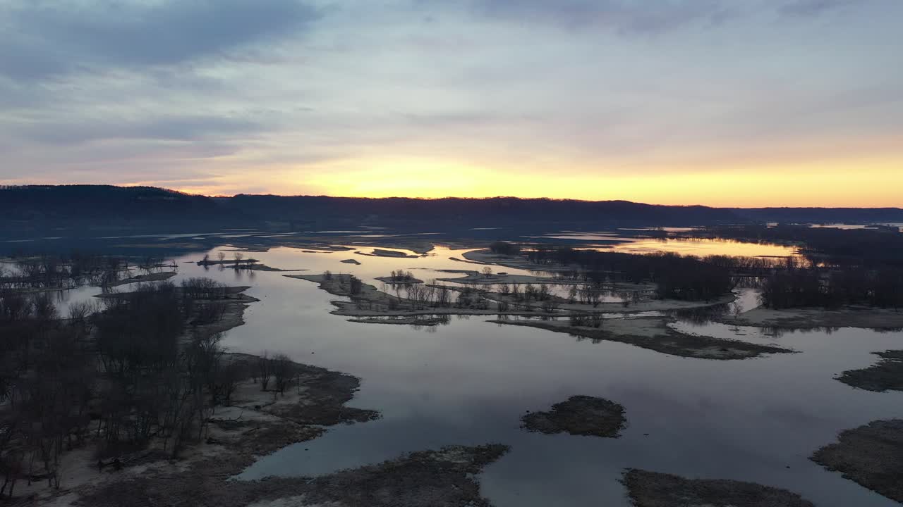 Luftfoto af flod- og vådområdelandskab ved gylden solopgang.