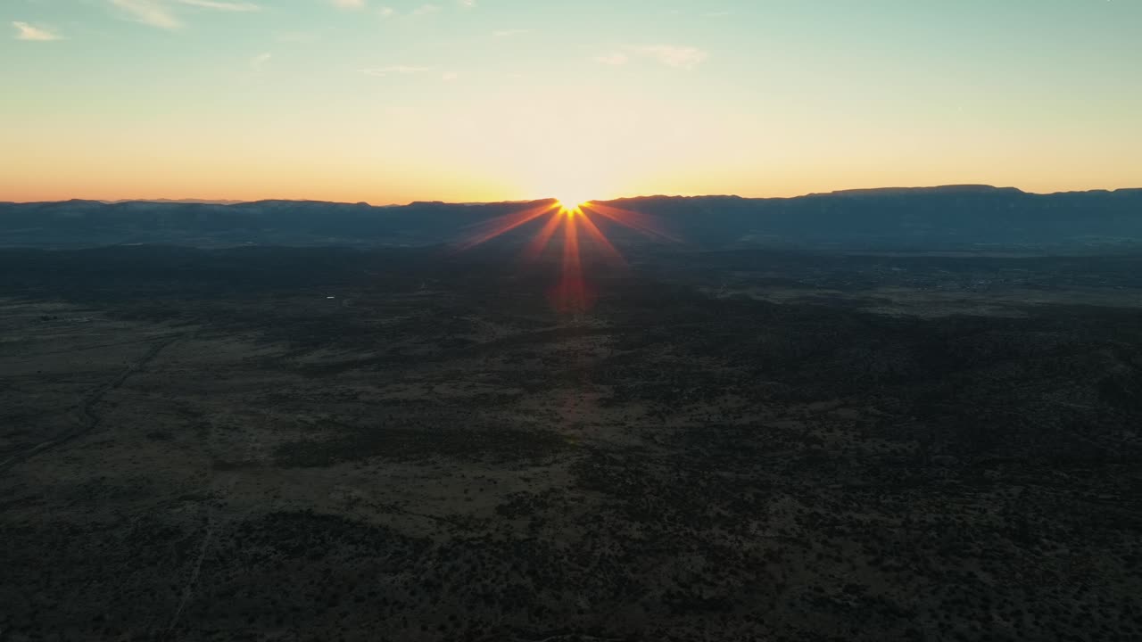 Atardecer sobre naturaleza árida con montañas y bosques