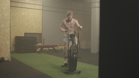 fitness man on bicycle doing spinning at gym. fit young male working out on gym bike. male exercising on bicycle in health club