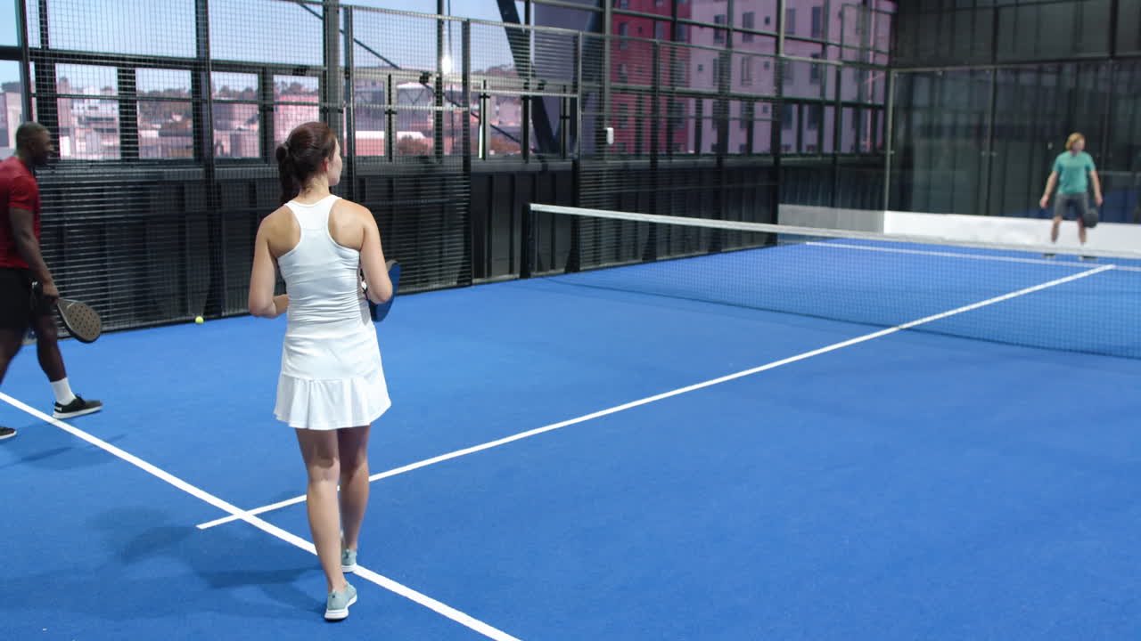 Diverse players enjoying intense padel tennis match on vibrant blue indoor court indoors