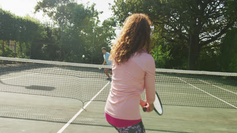 video di una coppia bi-razziale felice che gioca a tennis sul campo