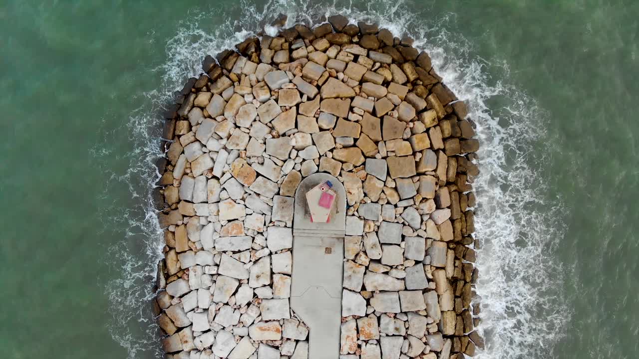 faro y olas rompiendo desde arriba con un dron