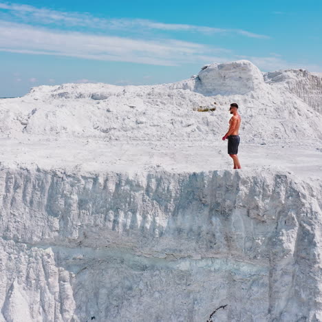 young sporty man in white mountains. healthy man without shirt walking along rocky canyon in a warm sunny day. aerial view.