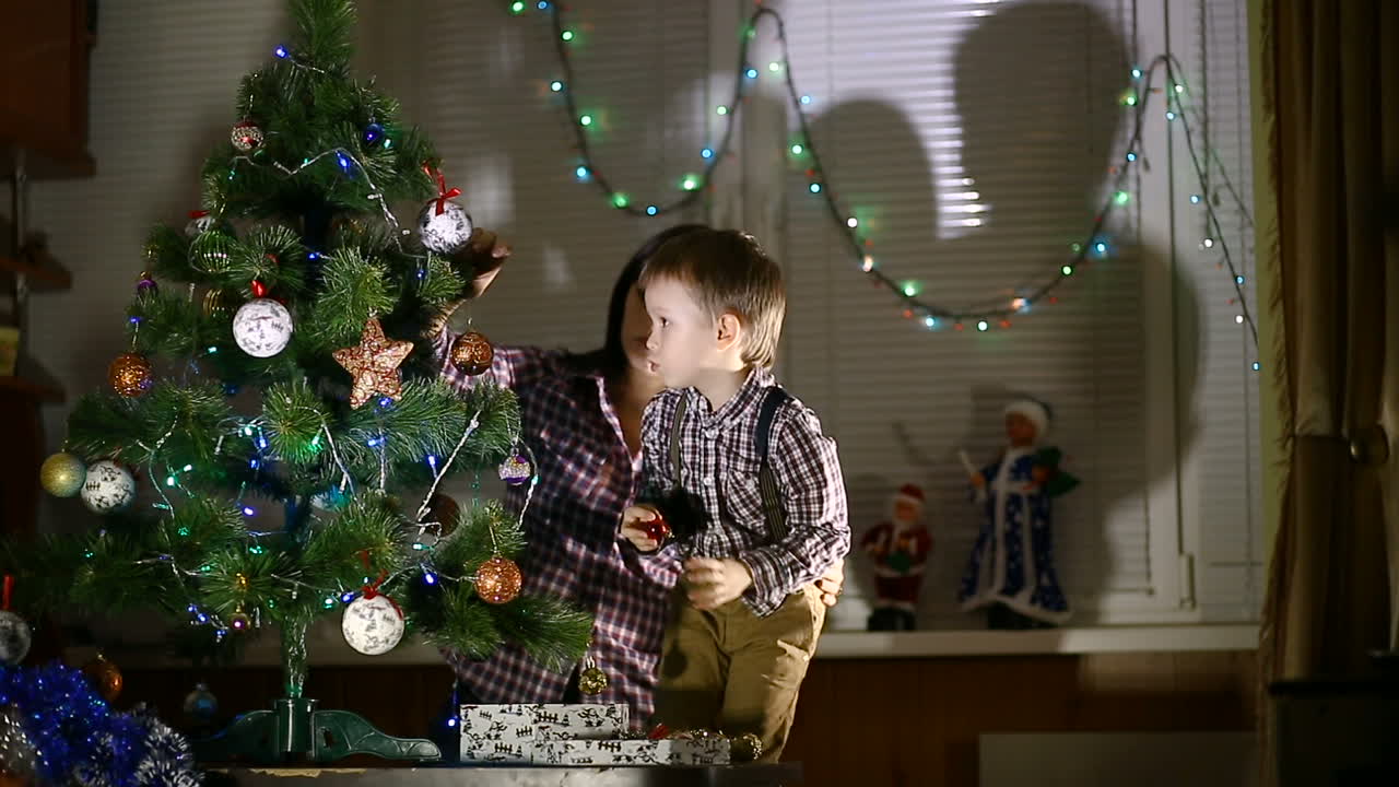 Family Decorating Christmas Tree. Happy family decorating a Christmas tree with boubles in the living-room