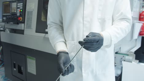 hombre inspeccionando la calidad de una barra de titanio en la fábrica.