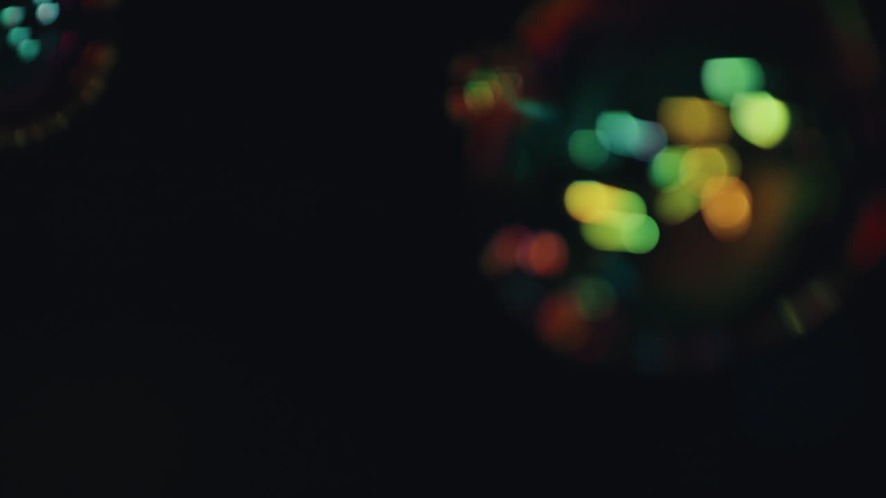 mujer de cerca soplando burbujas en el techo por la noche disfrutando de una noche lúdica con luces bokeh en el fondo