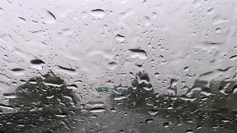 gotas de lluvia que caen sobre el cristal del coche del parabrisas mientras se conduce por la carretera con limpieza de limpiaparabrisas