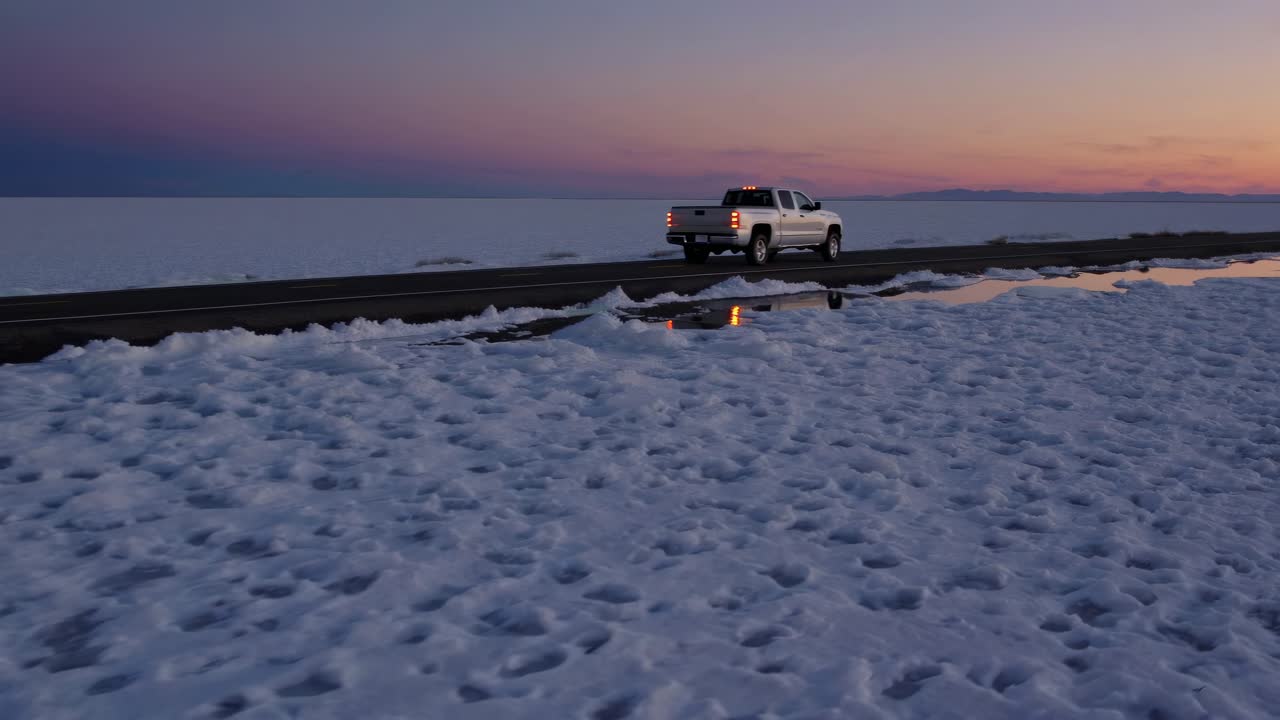픽업 트럭이 해가 지는 동안 소금 평평한 도로를 통해 운전