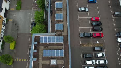 Aerial-rising-view-above-town-apartments-renewable-energy-solar-panel-rooftop-and-inner-private-carpark