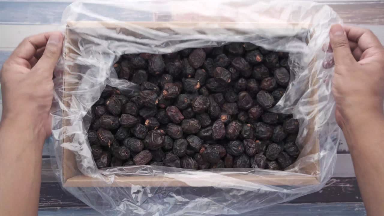 man's hand pick date fruit from a box , top down