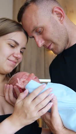 lovely caucasian couple holding a newborn. happy parents of a tiny boy. close up portrait. vertical video