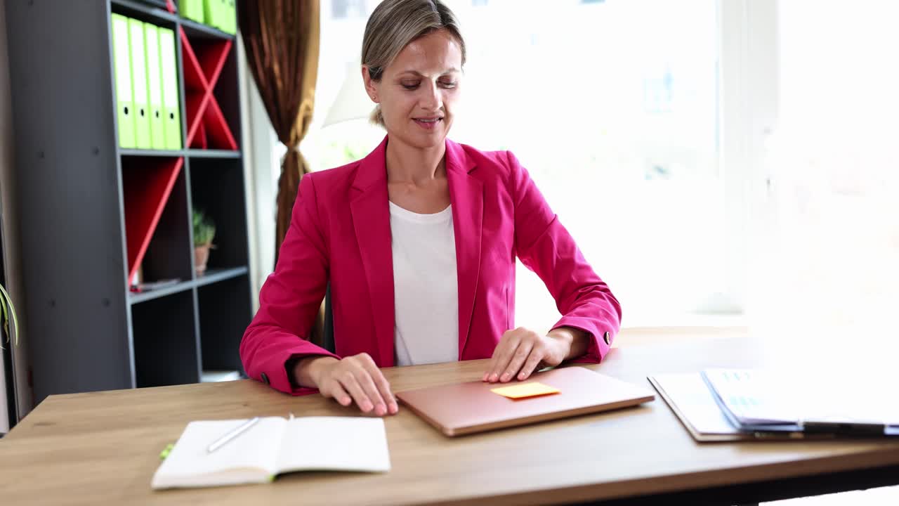 A smiling woman working on a laptop in a bright office