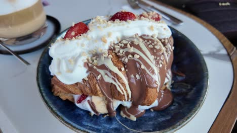 chocolate covered croissant with strawberries and whipped cream