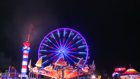 fireworks explode in the night sky behind a ferris wheel at a carnival or state fair 4