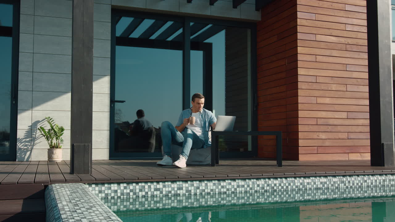 Happy man using laptop at luxury house