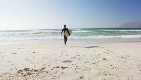 Male-surfer-walking-with-surfboard-at-beach-4k