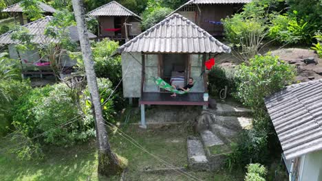 Entrepreneur-in-hammock-typing-on-laptop-in-hut-on-beach