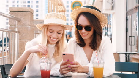 two friends enjoying drinks and mobile phone at an outdoor cafe