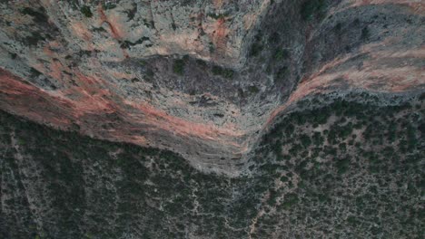 el avión no tripulado desciende por un acantilado intimidante con un paisaje de arbustos secos, se inclina hacia arriba y regresa a leonidio, grecia.