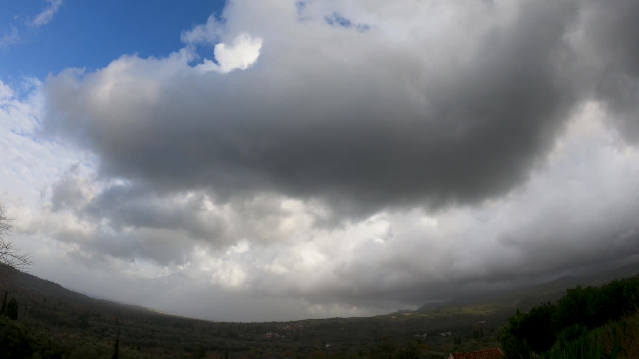 Dramatisk time-lapse af mørke stormskyer, der bevæger sig hurtigt hen over et grønt, bakket landskab, stemningsfuld vejrstemning med overskyet himmel og regn, der nærmer sig naturen