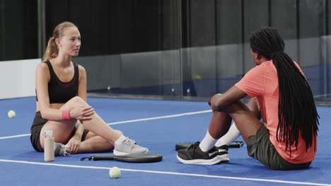 resting on court, two diverse players enjoying break after intense padel tennis match
