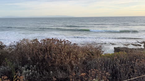 caution cliff edge sign overlooking calm ocean at dusk