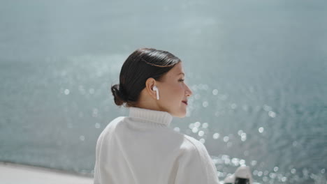 relaxed girl listening music in earbuds sitting at waterfront closeup vertically