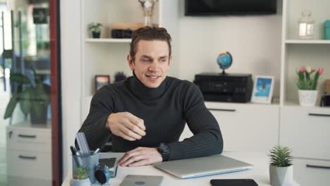 The-man-is-sitting-at-a-table-and-talking-to-the-camera,gesturing-with-his-hands,-then-he-starts-laughing-and-shows-a-thumbs-up-gesture