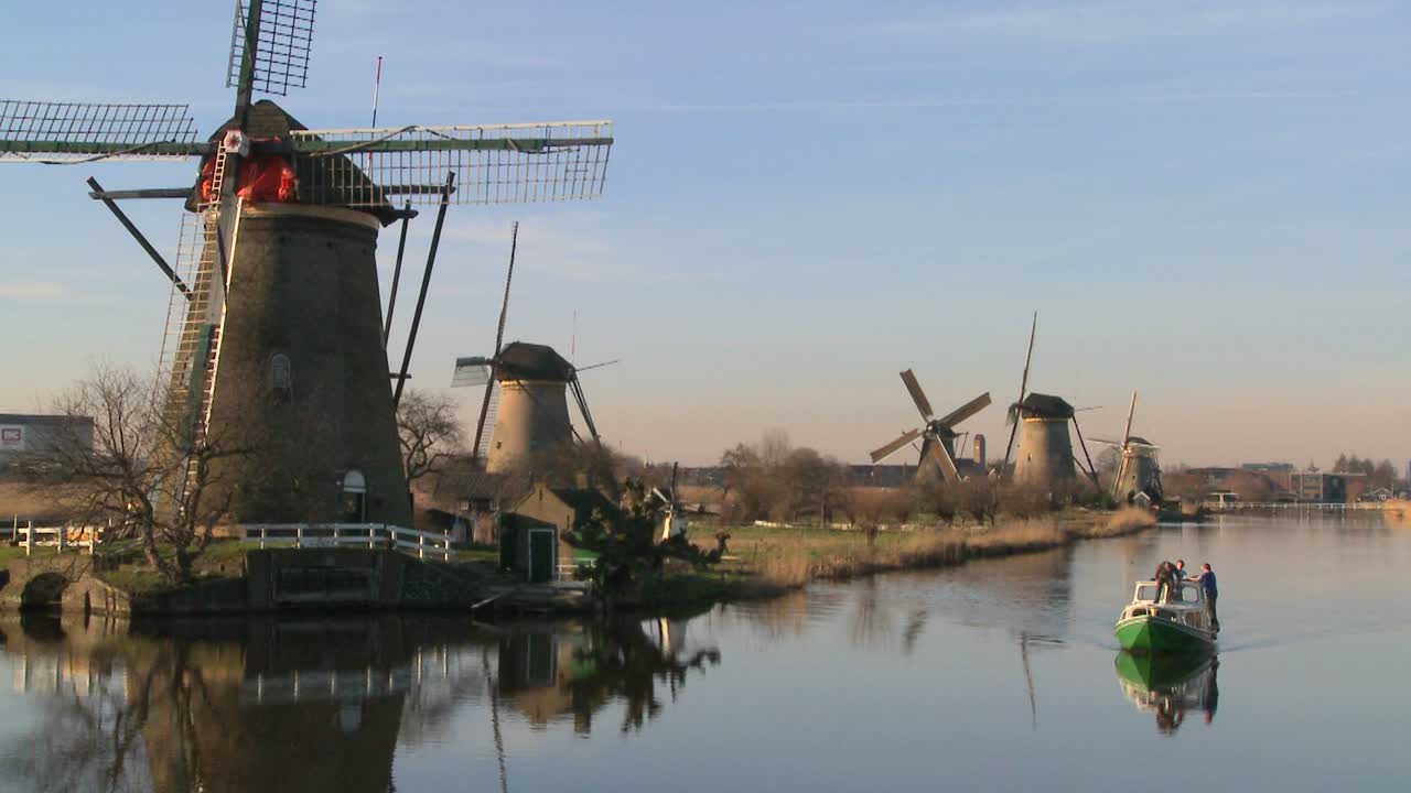 풍차가 근처에 있는 네덜란드의 운하를 따라 보트가 이동합니다. 3