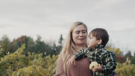 happy mother holds an asian baby in her arms who eats an apple