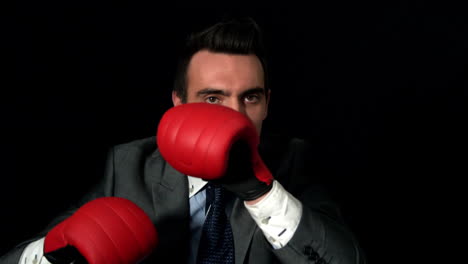 hombre de negocios golpeando con guantes rojos sobre fondo negro