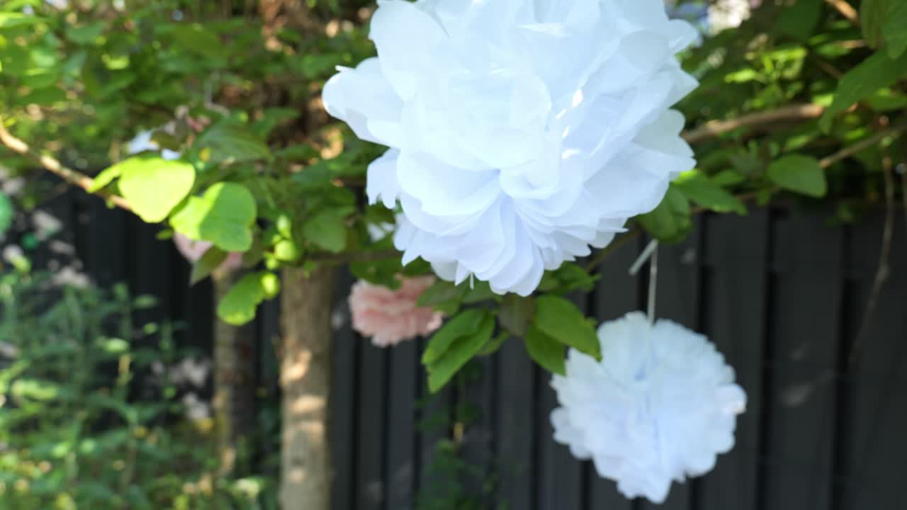 색 종이 꽃 장식은 은 날에 정원에서 매달려 있습니다.