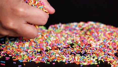 hands interacting with colorful sprinkles on surface