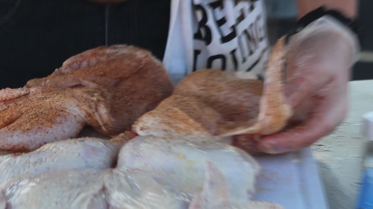 vista de cerca de una variedad de pollo crudo en una tabla de plástico grande de corte como el pollo se cubre completamente en condimentos