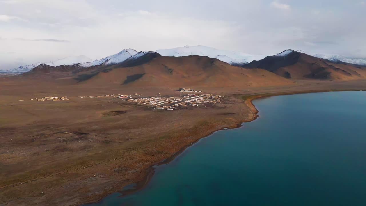 drone approach Karakul village on the shore of Lake Karakul, Pamir Mountains, Tajikistan high angle aerial