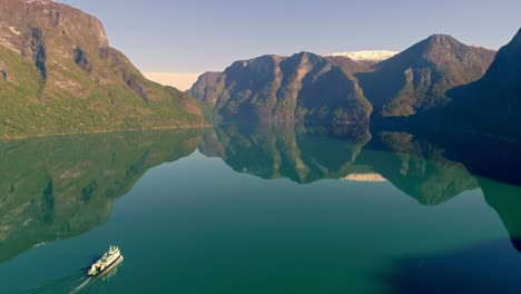 Inclinación-Aérea-Hacia-Arriba-De-Un-Crucero-Gigante-En-Un-Fiordo-Verde-Y-Tranquilo-Entre-Montañas-En-Noruega