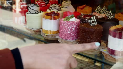 a woman is pointing at a cake in a bakery showcase