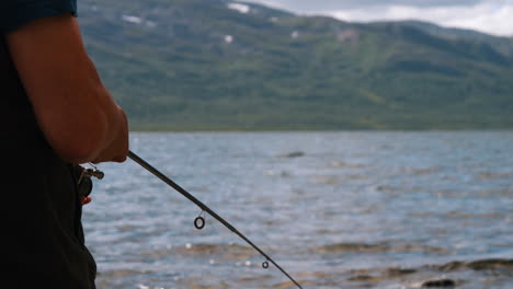 Primer-Plano-De-Las-Manos-De-Un-Pescador-Usando-Caña-De-Fundición-En-Un-Hermoso-Paisaje