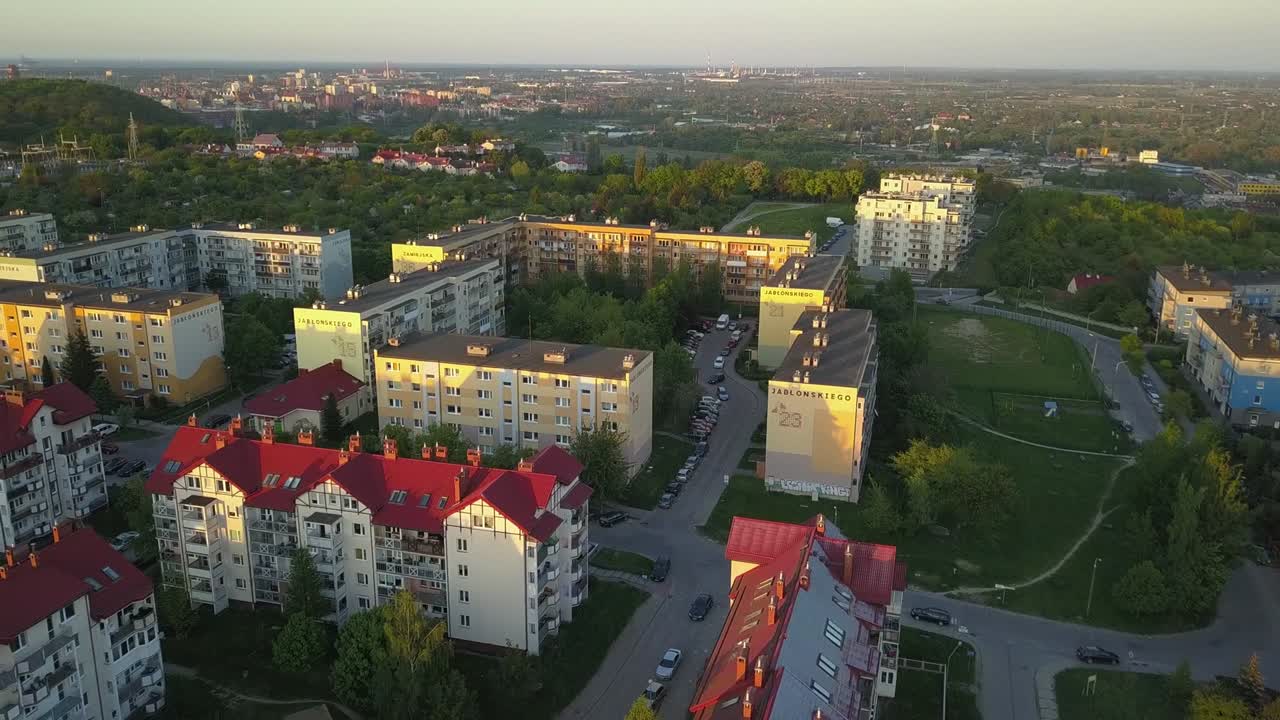 Аэрофотосъемка жилого района на закате с многоквартирными и частными домами.