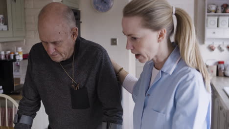 caregiver assisting elderly man with crutches in the kitchen