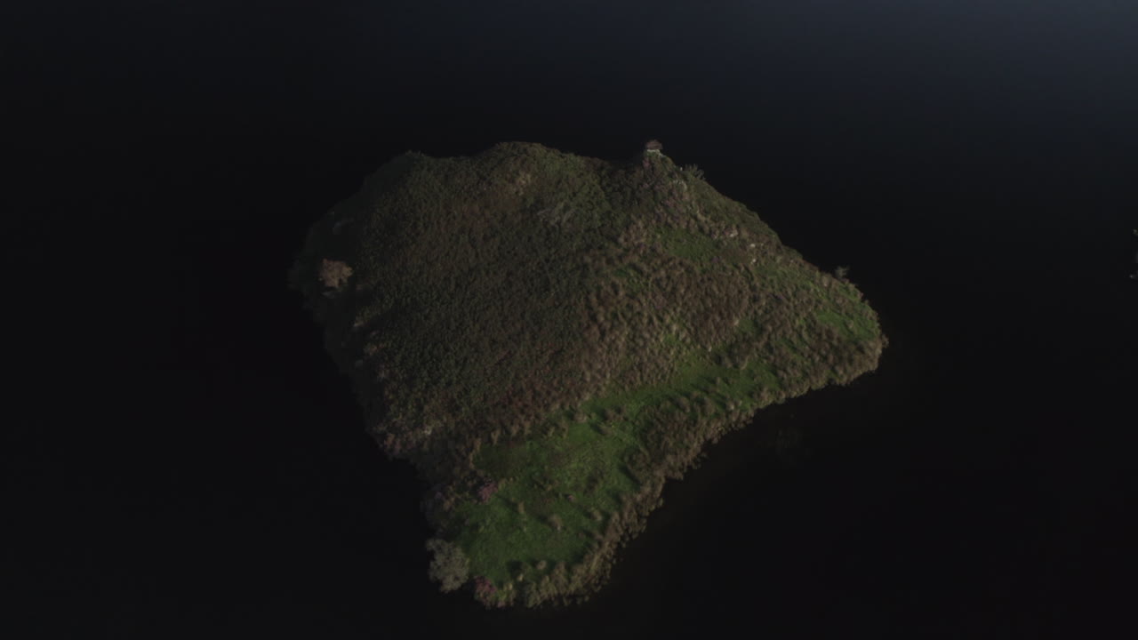 Drone footage of a partial flyover above the island in Llyn y Dywarchen, North Wales. Also called Turf Island or Floating Island, this grassy land is surrounded by dark water in a rural landscape