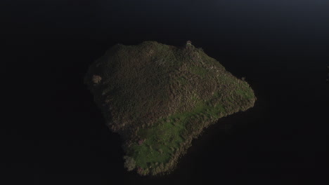 drone footage of a partial flyover above the island in llyn y dywarchen, north wales. also called turf island or floating island, this grassy land is surrounded by dark water in a rural landscape
