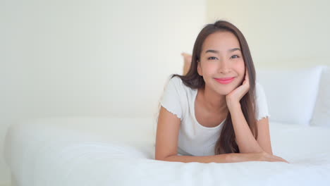 a young woman lying on a hotel suite bed smiles