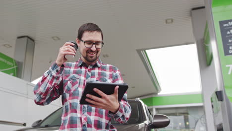 man using tablet at a gas station