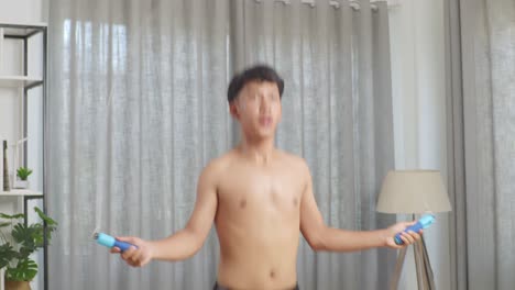 아시아 십대 소년 은 집 에서 셔츠 를 벗고 운동 을 하면서 줄 을 뛰어넘는다