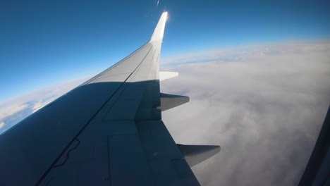 a pov from a persons eyes as the lean over toward the window of an airplane and look out into the blue sky