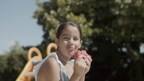 cute girl eating watermelon and smiling enjoying hot summer day.