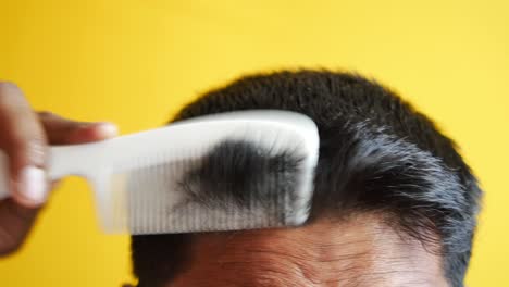 man styling hair with comb close up