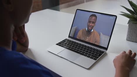 Mid-section-of-african-american-woman-having-a-video-call-on-laptop-with-male-colleague-at-office