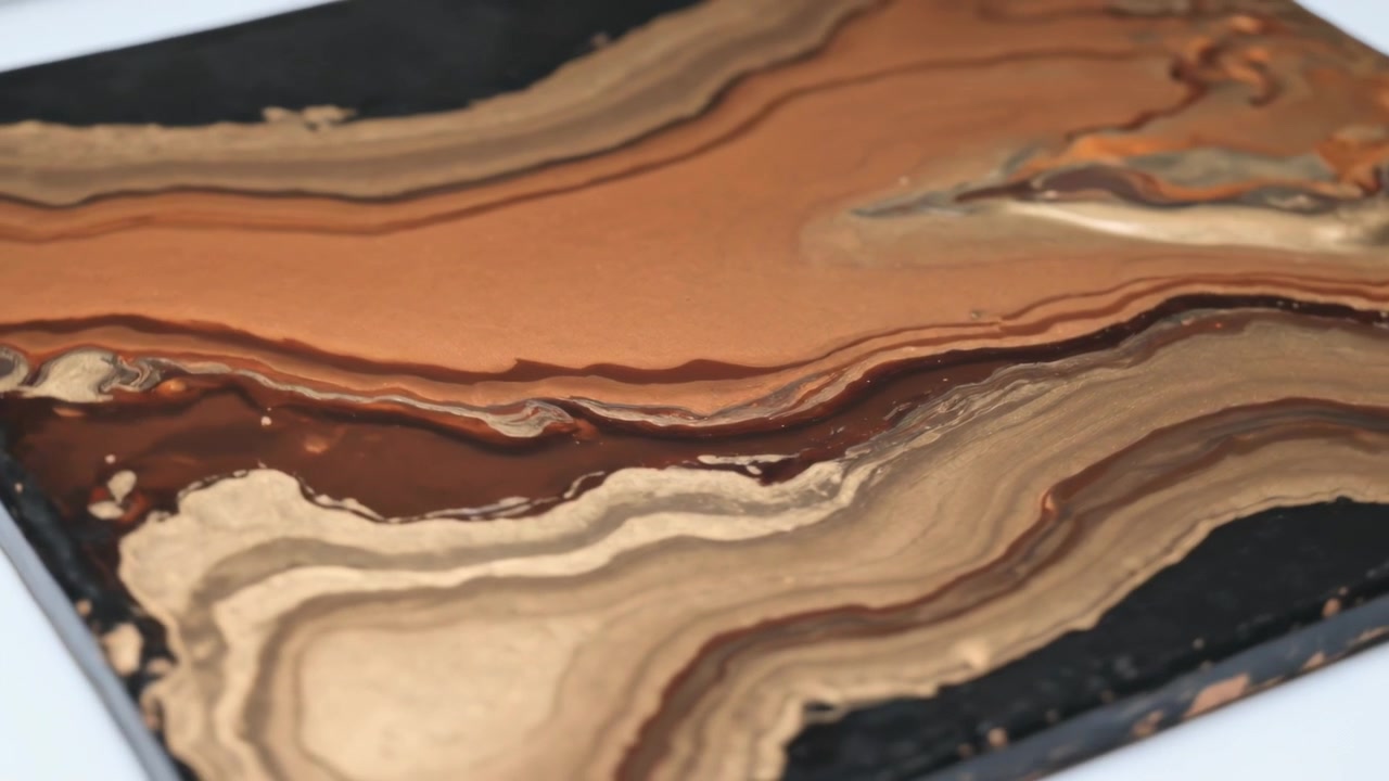 La telecamera panoramica mostra un pannello dipinto su un tavolo bianco per rivelare una texture lucida a strati e gocciolamenti.